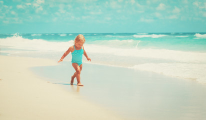 Fototapeta na wymiar little girl run play with waves on the beach