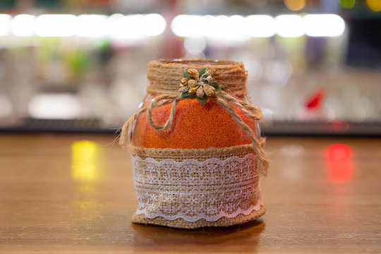 little orange balls in a decorative jar on a wooden surface. wax immersion