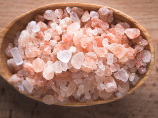 Fototapeta na wymiar Large pink salt and wooden spoon on wooden table. 