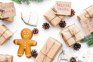 Christmas traditions. Gift boxes with notes Santa Secret near spruce branch and gingerbread cookies on white background top view