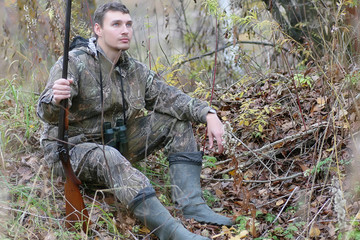 Man in camouflage and with guns in a forest belt on a spring hun
