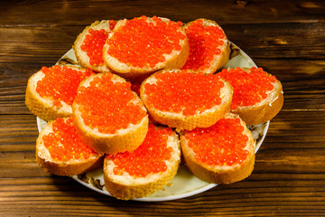 Sandwiches with red caviar on wooden table. Top view