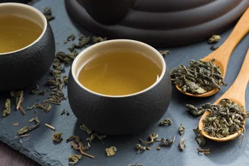 Foto auf Acrylglas Tee pialas with green tea on a dark background, close-up