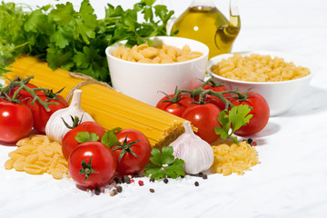 spaghetti, tomatoes and fresh ingredients on a white table