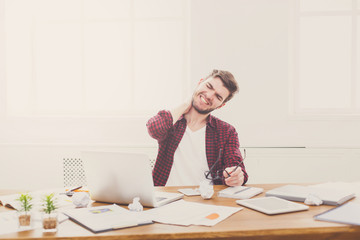 Naklejka premium Tired, overworking businessman with laptop in modern white office