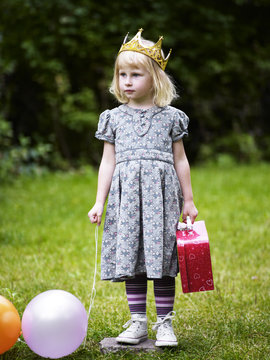 Scandinavia, Sweden, Stockholm, Girl standing in park holding balloons and bag