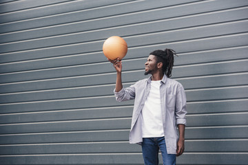 handsome african american man with basketball ball at street