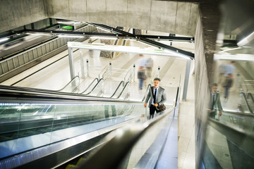 Businessman on an escalator on a metro station.