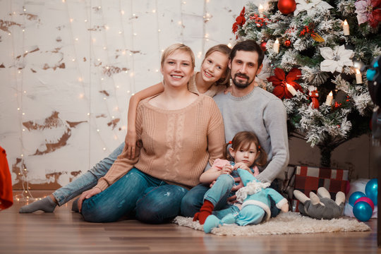 New Year's photo of family sitting at decorated Christmas tree