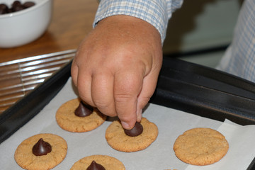 Close-up pressing chocolate into a peanut butter cookie