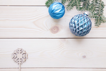 Christmas light wooden background with fir tree branches and blue Christmas tree balls. Close up. Copyspace