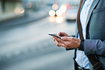 Businessman with smartphone in a city.