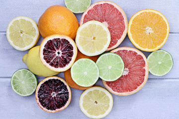 Fototapeta na wymiar Variety of citrus fruits (orange, blood oranges, lemons, grapefruits, and limes) over a blue wood table top rustic background. Image shot from overhead.