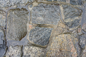 The texture of the old, wet granite in the masonry of the wall