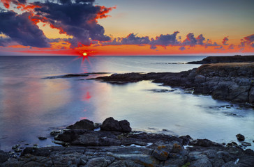 Fototapeta premium Beautiful sunrise on rocky shore and dramatic sky clouds