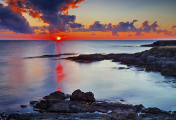 Beautiful sunrise on rocky shore and dramatic sky clouds