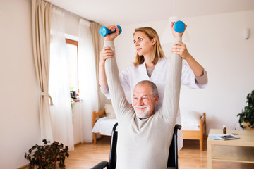 Nurse and senior man in wheelchair during home visit.