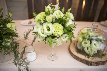 Fresh eustoma roses bouquet composition on a table in a glass vase. Wedding bridal decor. Dim dark sunset light. Romantic mood