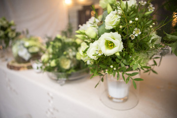 Fresh eustoma roses bouquet composition on a table in a glass vase. Wedding bridal decor. Dim dark sunset light. Romantic mood