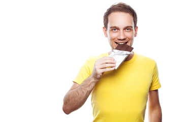 Sweet tooth concept. Portrait of smiling handsome young guy holding tablet of milk chocolate wrapped in silver foil and posing over white background. Copy-space. Close up. Studio shot