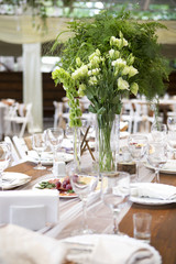 Fresh eustoma roses bouquet composition on a table in a glass vase. Wedding bridal decor. Dim dark sunset light. Romantic mood