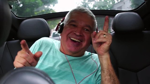 Happy senior man listening music in the car
