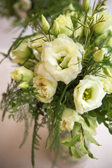 Obraz na płótnie Canvas Fresh eustoma roses bouquet composition on a table in a glass vase. Wedding bridal decor. Dim dark sunset light. Romantic mood