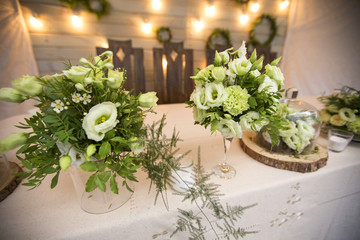 Fresh eustoma roses bouquet composition on a table in a glass vase. Wedding bridal decor. Dim dark sunset light. Romantic mood