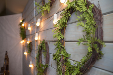 Wreath natural garland decorated with bulb lights on a wooden background on wedding ceremony. Dim light