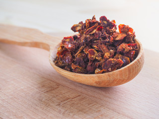 Spice dried tomato and wooden spoon on a wooden table.
