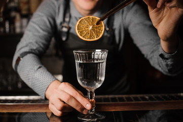 Barman decorating a clear alcoholic drink with a slice of lemon