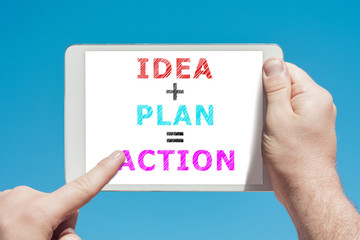 Man holding a tablet device with text idea plan action on the screen