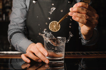 Bartender decorating a glass with splashing drink - obrazy, fototapety, plakaty