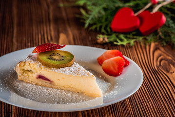 Cheesecake on Valentine's Day with strawberry and hearts on fir and wood background