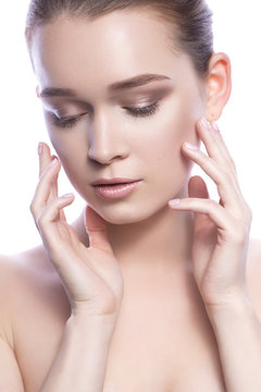 Beautiful brunette caucasian woman with fresh clean skin and neutral nude make-up and ponytail hairstyle posing sensually on a white isolated background. Young girl. Skincare. Copy space