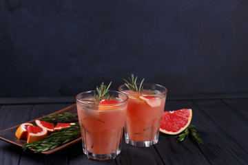 Refreshing detox cocktail of grapefruit and rosemary on dark wooden table, food background with copy space for text design