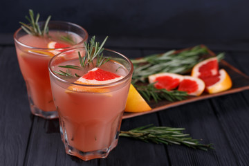 Refreshing grapefruit lemonade with ingredients on dark background, selective focus