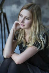 Cute blonde caucasian woman sitting in loft grunge trendy minimalistic interior, smiling cheerfully