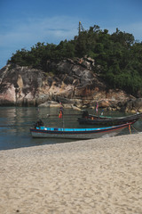 Fototapeta na wymiar rocky coast near sandy beach with old boat on sunny day