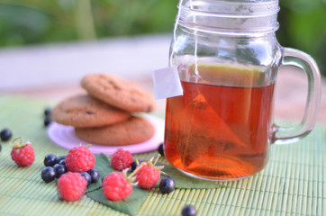 Cup of tea with cookies and berries on table close-up
