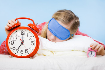 Sleeping woman wearing pajamas holding clock