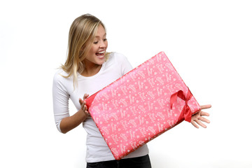 Hübsche blonde Frau schaut begeistert auf ein Weihnachtsgeschenk