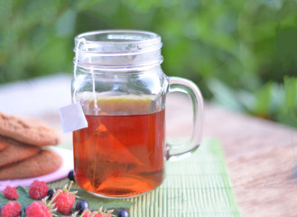 Cup of tea with cookies and berries on table close-up