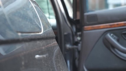 Hand of male businessman opens and holds the car door for the beautiful young woman. Man opening door of automobile for female passenger. Girl coming out of the auto. Close up Slow Motion