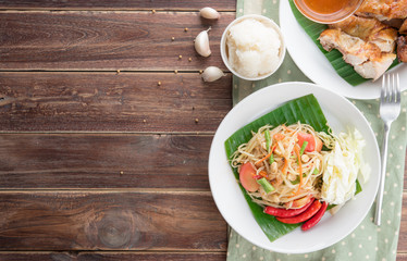 Green papaya salad,Som tum Thai and grilled chicken on wood table,top view