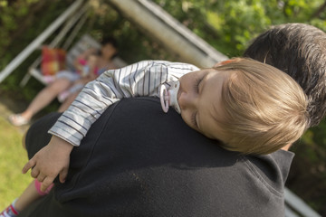 a tired, beautiful child slept on his father's shoulder