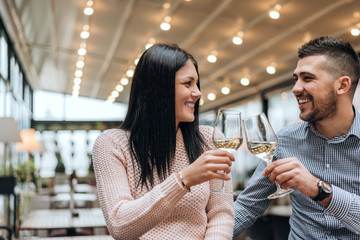 Couple toasting wine glasses at restaurant.