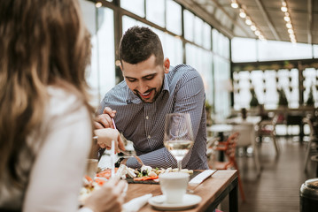 Handsome man in restaurant with friend eating.