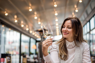 Attractive young woman in cafe restaurant tasting wine.