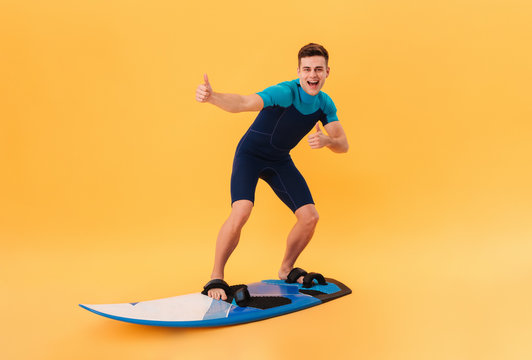 Image of Cheerful surfer in wetsuit using surfboard